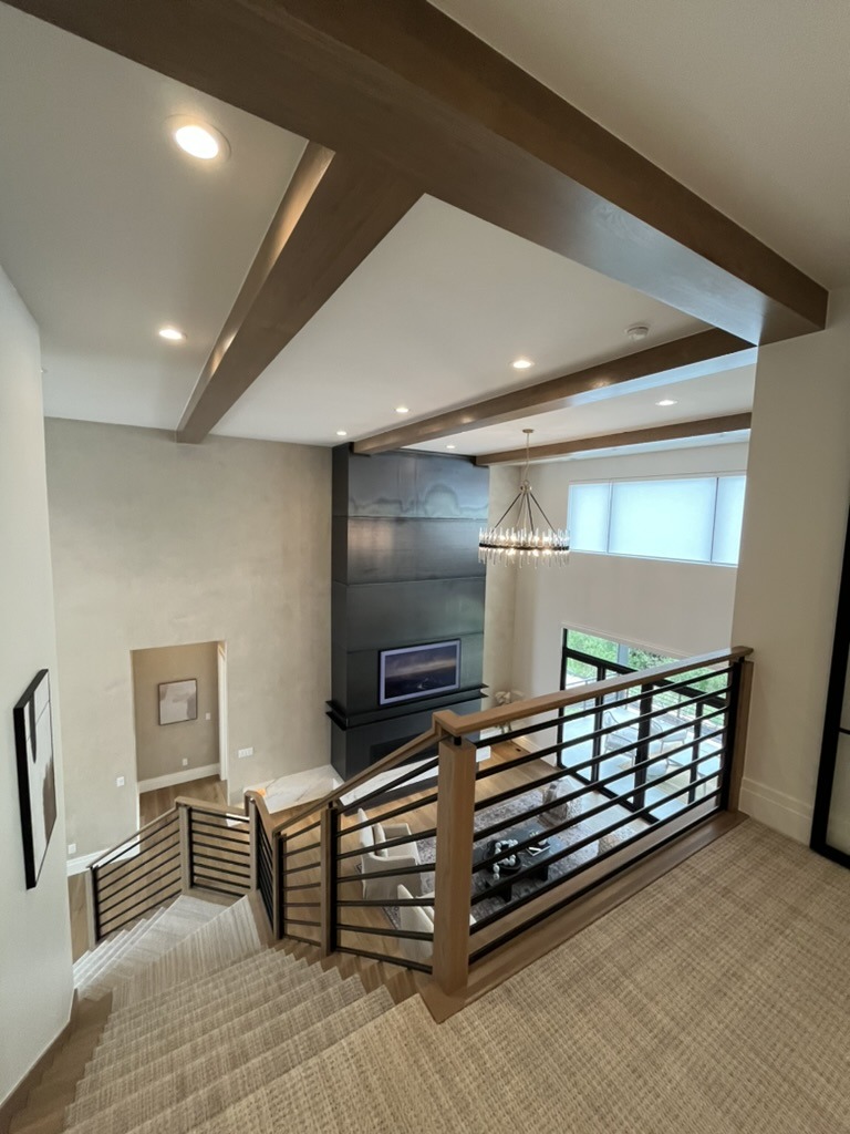 Open staircase overlooking great room with custom beams