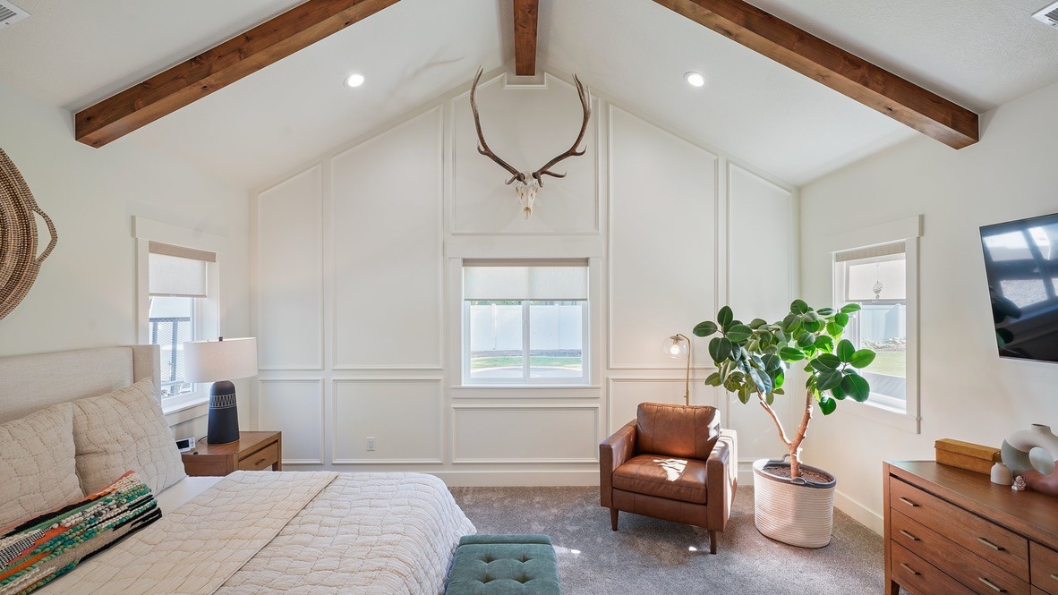 Vaulted master bedroom with ceiling beams and wainscoting
